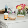 Our Oh baby! Belly Oil, uncapped on a dresser, along with many of our other products behind it