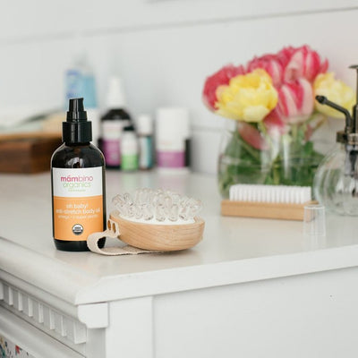 Our Oh baby! Belly Oil, uncapped on a dresser, along with many of our other products behind it
